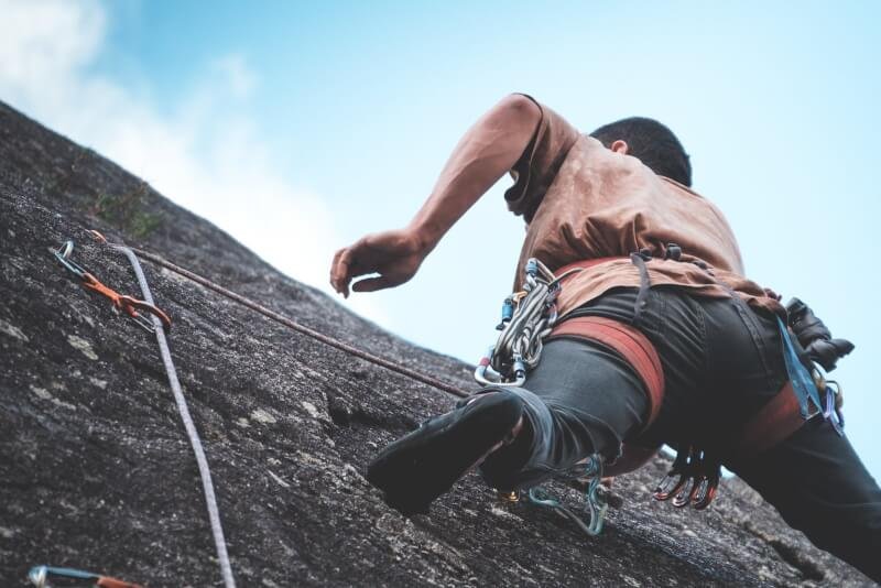 Unrecognizable mountaineer climbing on cliff