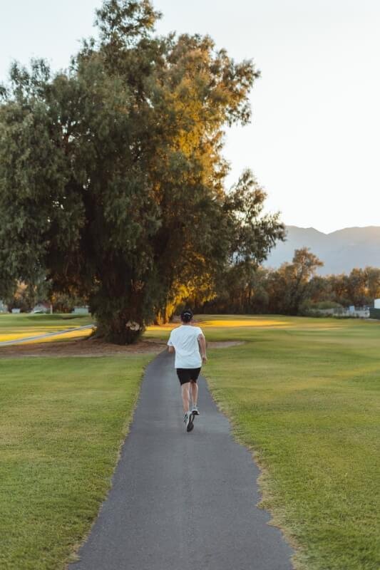 Unrecognizable woman jogging along footpath in park